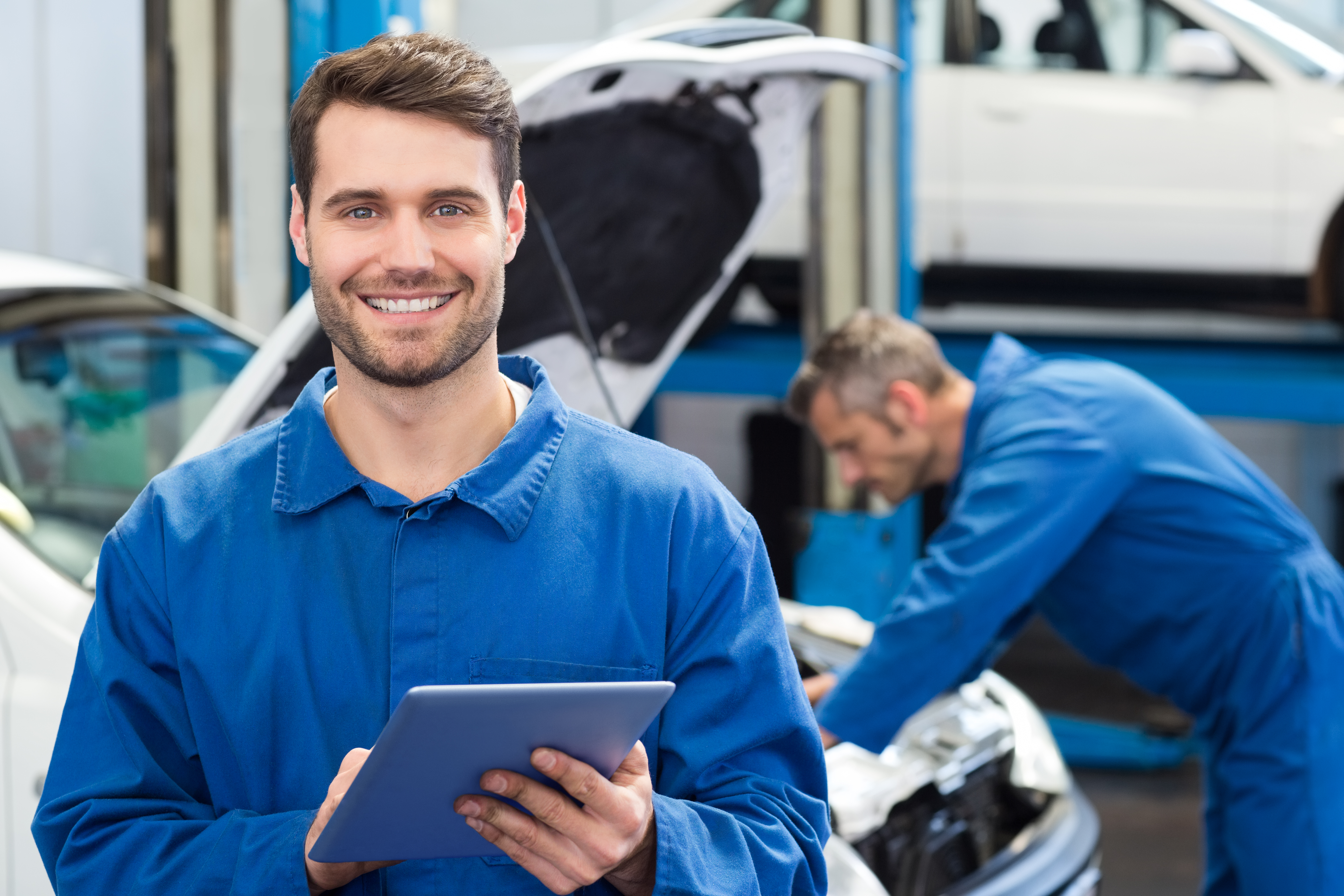 Image of a smiling mechanic using a tablet in a workshop